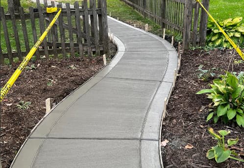 concrete walkway recently poured between fence
