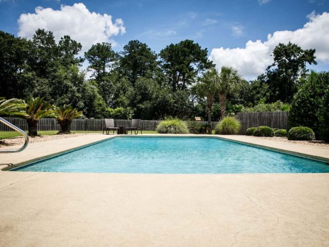 concrete pool deck with trees in background
